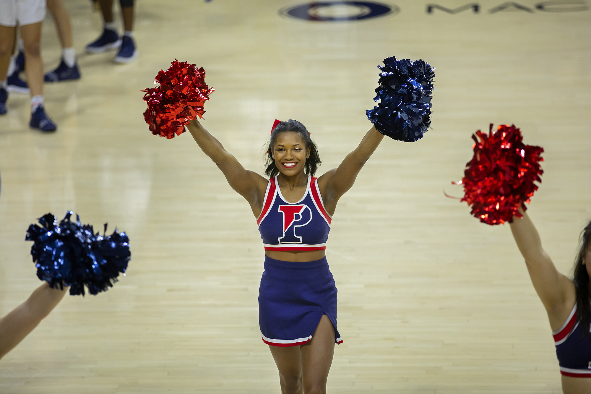 Maya Moore cheers with her pom-poms on the basketball court with her fellow cheerleaders.