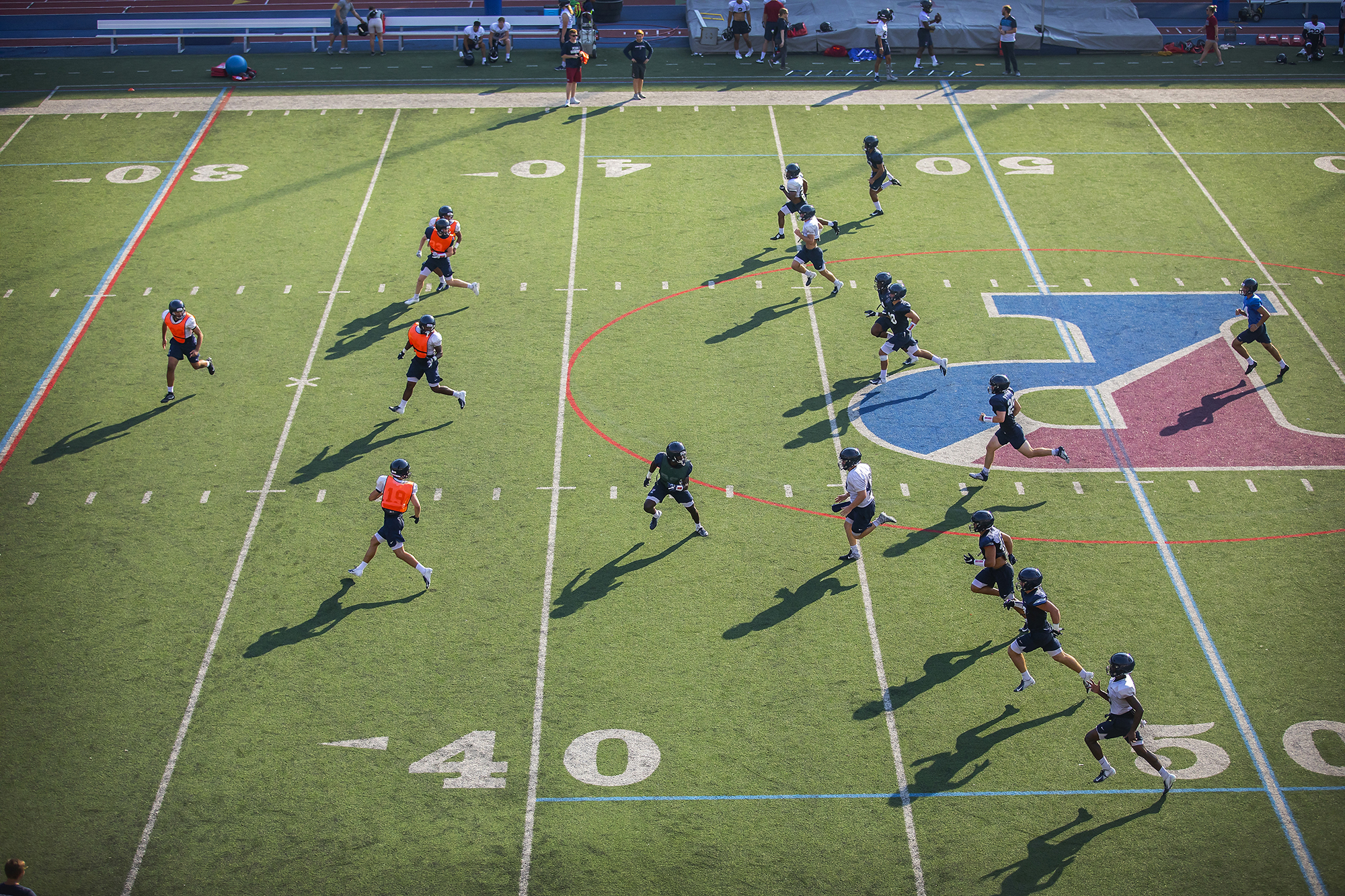 Football players run through drills on Franklin Field during preseason practice.