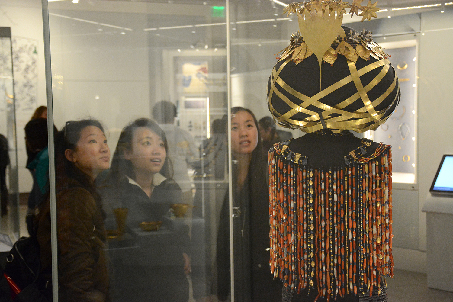 Students staring at Queen Puabi's headdress through glass case