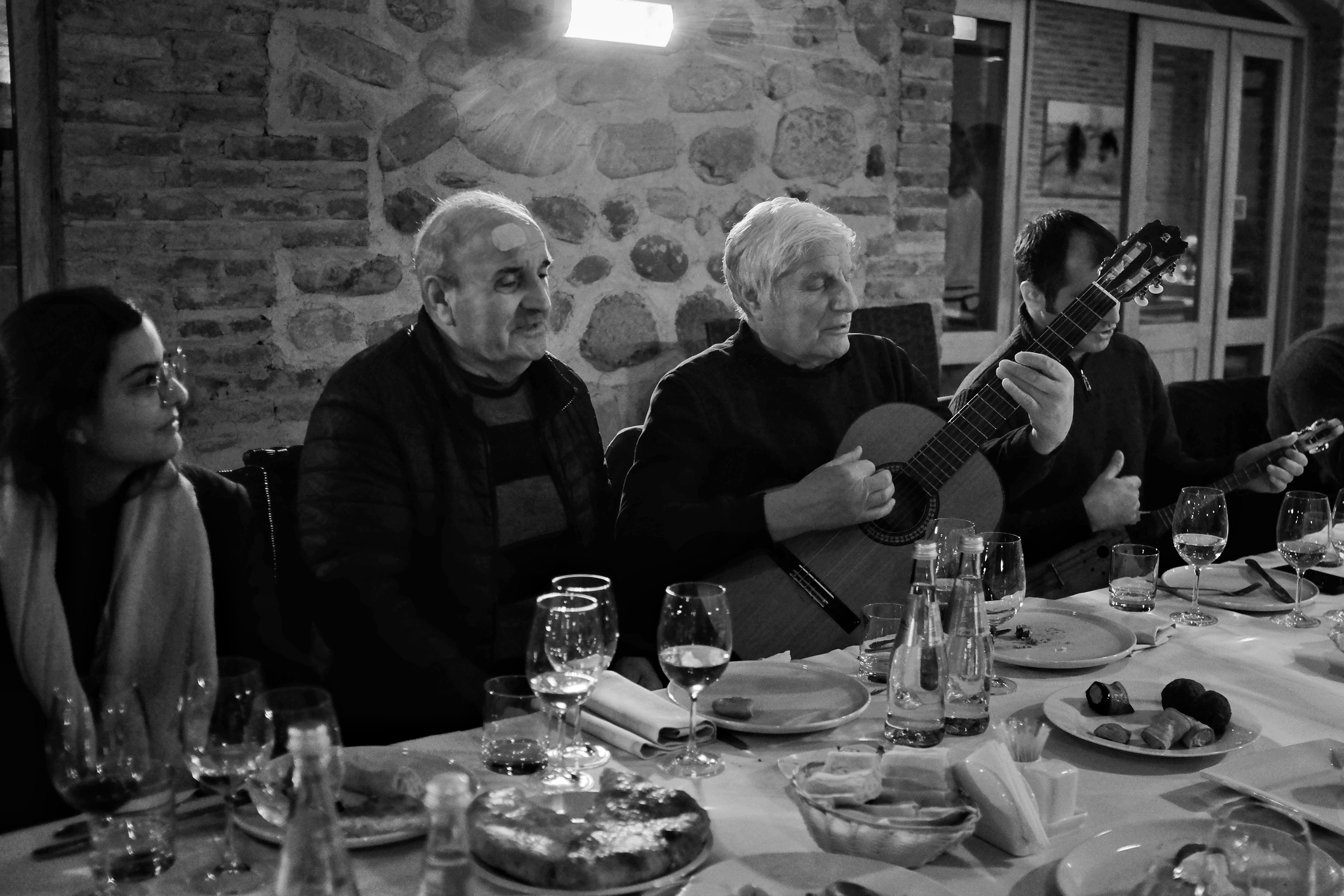 Georgian toastmaster playing a guitar at a dinner table. 