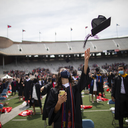 Graduates on Franklin Field throw graduation caps in the air.
