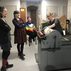 A person demonstrates the use of a letterpress machine while three others observe