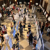 rows of posters on easels with groups of people around them in a historic hall