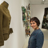Ruby Chisti in a gallery space in front of a coat presented as artwork.