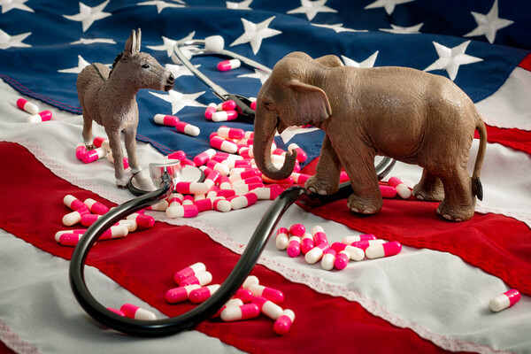donkey and elephant figurines on an american flag standing among pills and a stethoscope