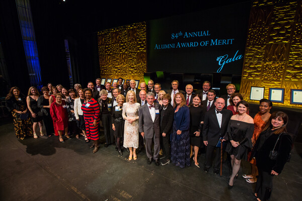 Alums and President Gutman pose for a photo on stage at the Gala