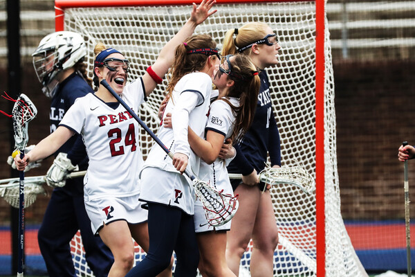 Penn women's lacrosse players celebrate after scoring a goal.