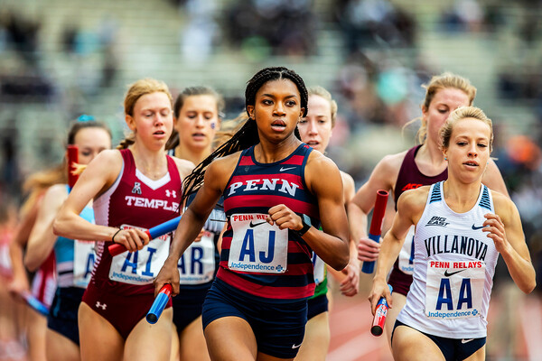 Nia Akins runs with a baton in her hand at the 2019 Penn Relays.