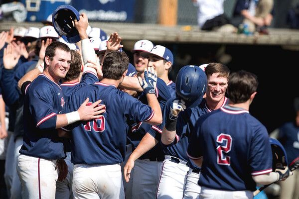 Players on the Penn baseball team celebrate and high five in a group.