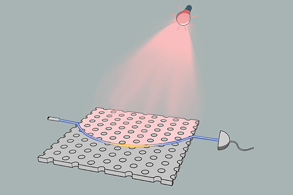 a pink light shining onto a flat sheet with holes on the top, a blue laser light shines from one end of the flat sheet to the other