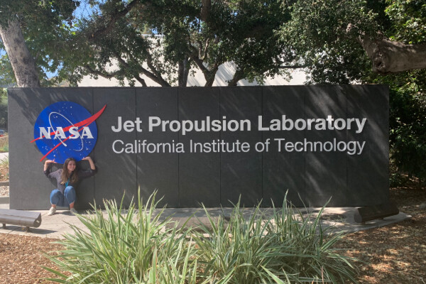 alex ulin standing in front of the jet propulsion laboratory sign, under the nasa logo and next to text that reads california institute of technology