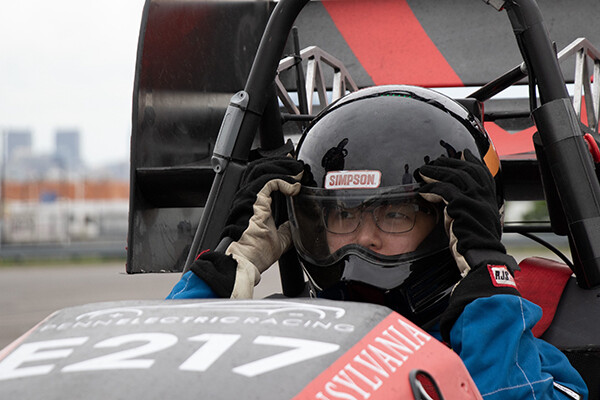 Kathie Jin adjusts her helmet inside a Penn Electric Racing car.
