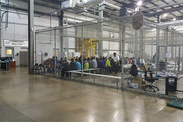 Group of people inside a caged room in an immigration detention center in Texas.