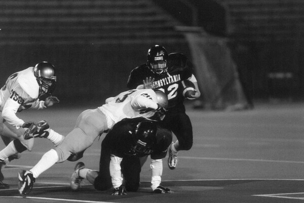 Tim Ortman, a running back, runs with the ball while stiff-arming a defender during a game in 1999.