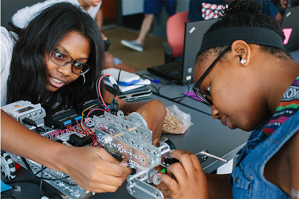 two middle school-age students work on a robotics project.