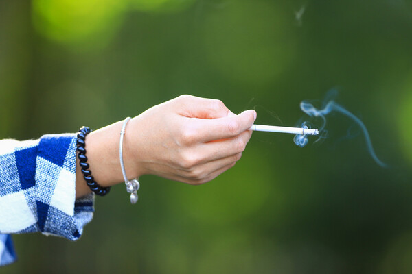 A teen’s hand holding a cigarette.