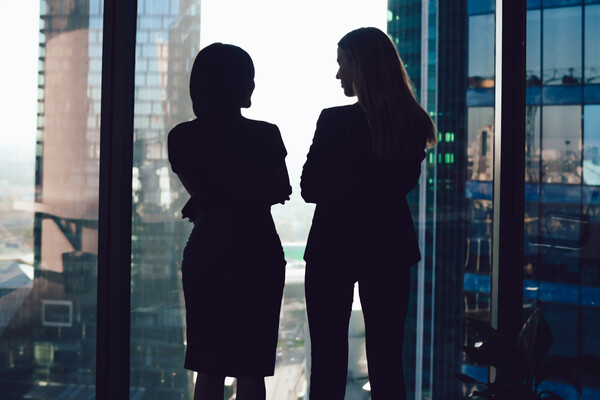 Silhouettes of businesswomen in modern office near a window.